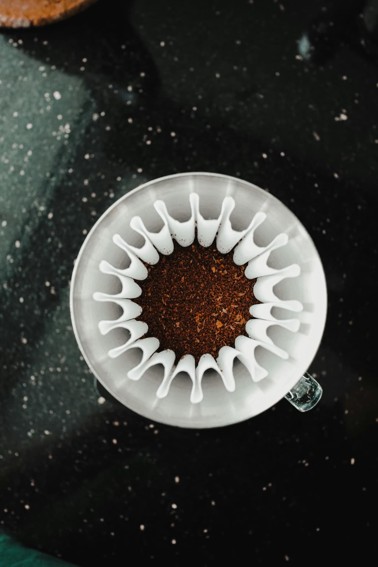 Top-down view of an Origami dripper loaded with ground coffee